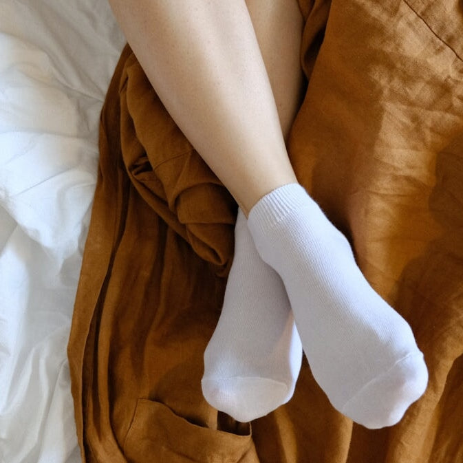 person wearing white socks lying on bed
