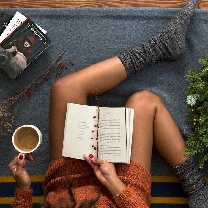 opened book on person's lap with gray socks